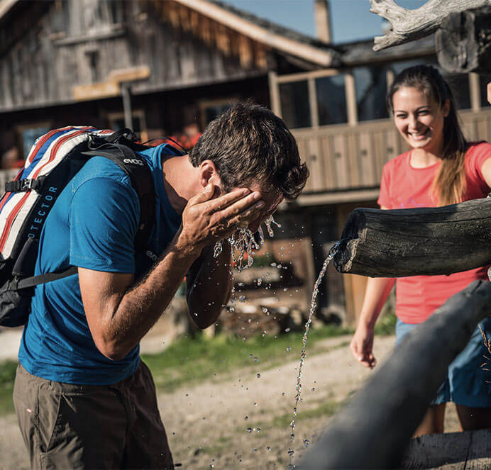 Frühling Wanderung - Mann wäscht Gesicht mit Wasser & Frau lacht - Hotel Terentnerhof
