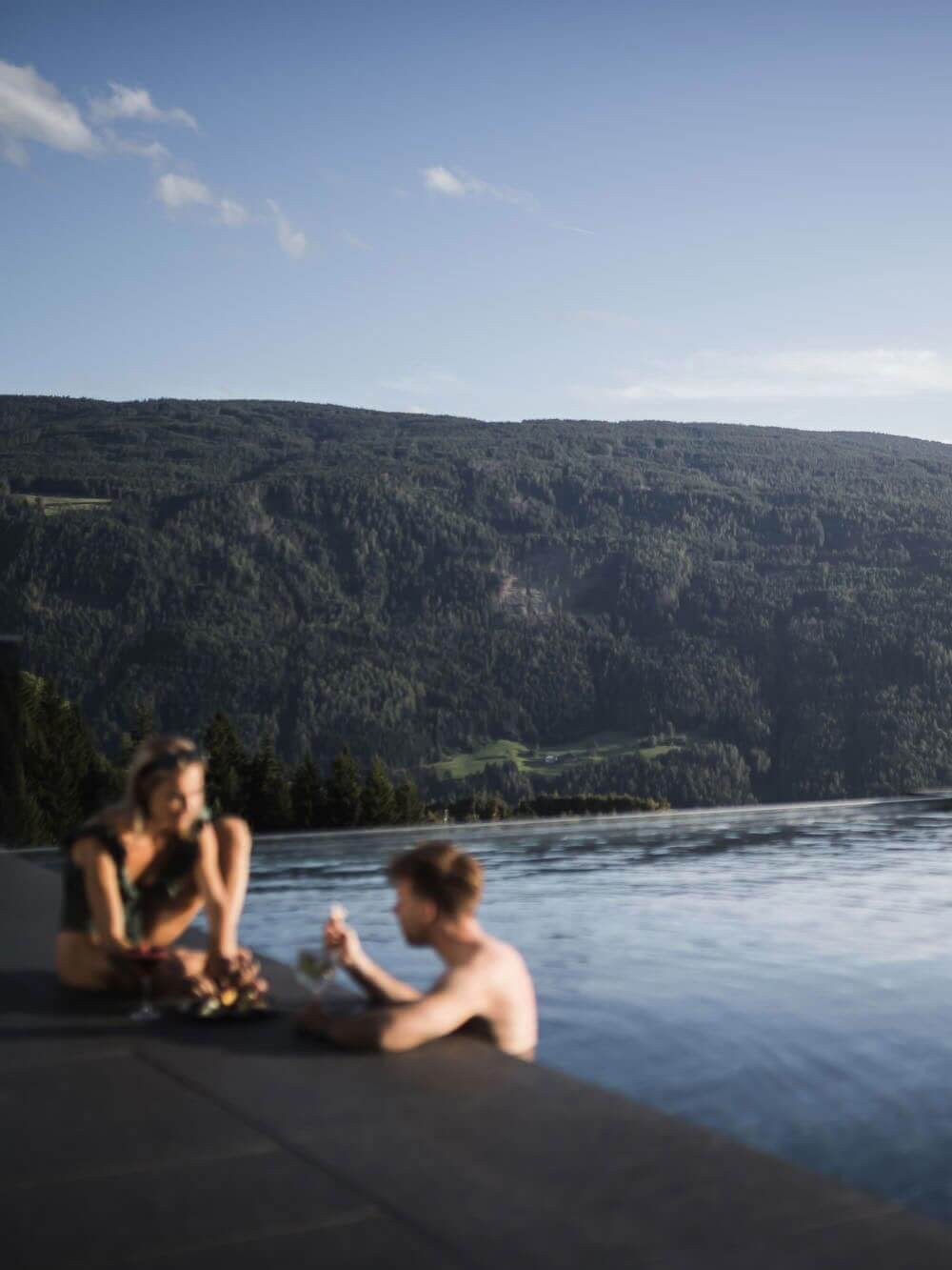Mann & Frau im Außenpool vor Panorama Terenten - Hotel Terentnerhof